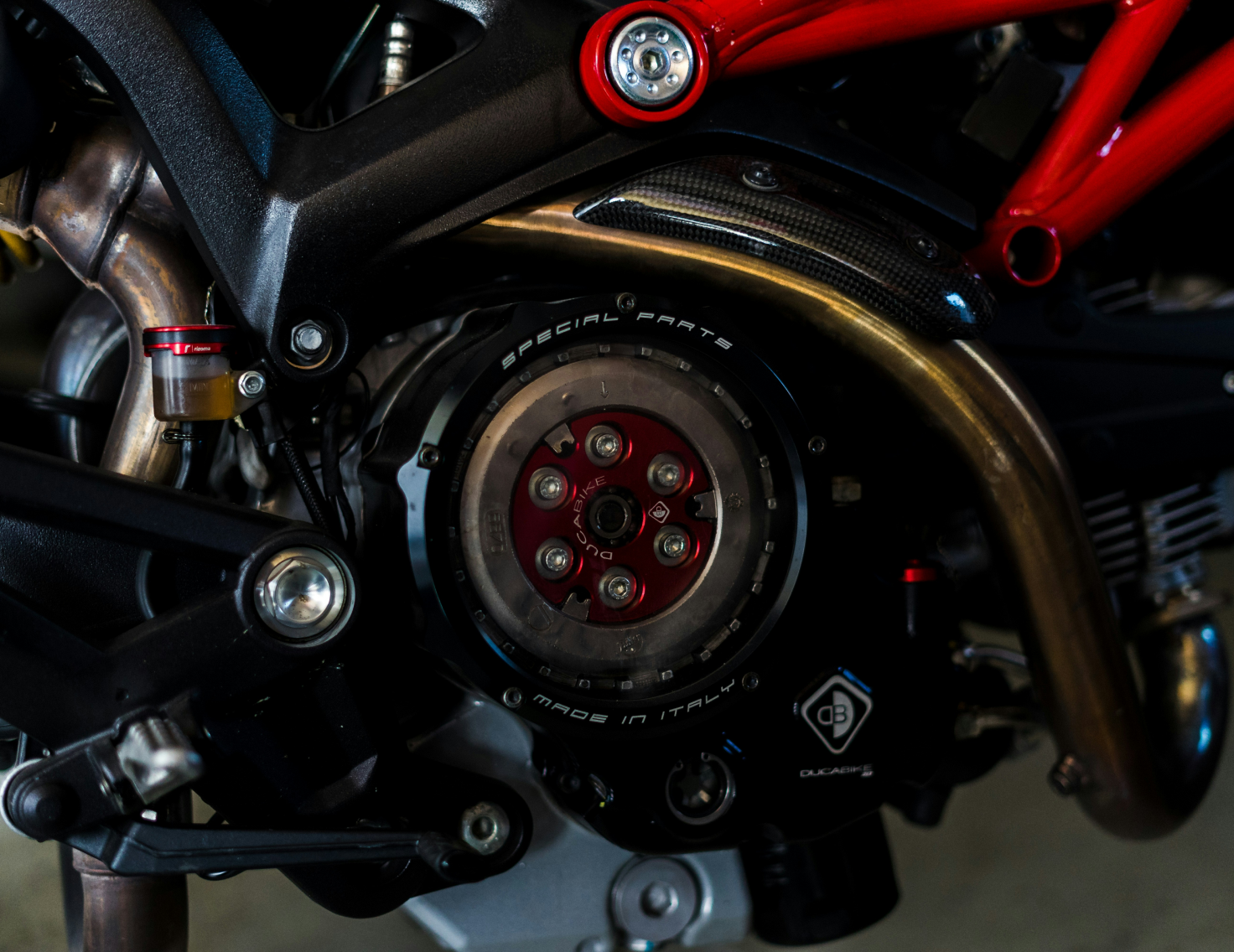 Partie moteur de moto avec cadre rouge et pièces métalliques visibles.