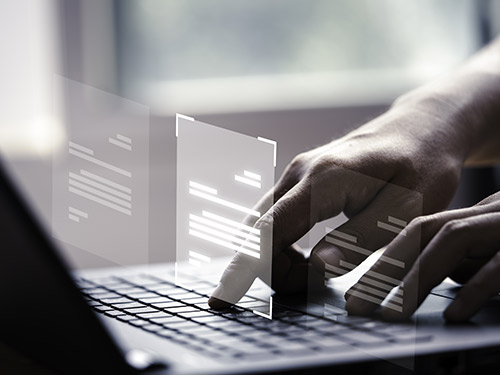 homme en train de taper sur son clavier d'ordinateur avec des documents virtuels
